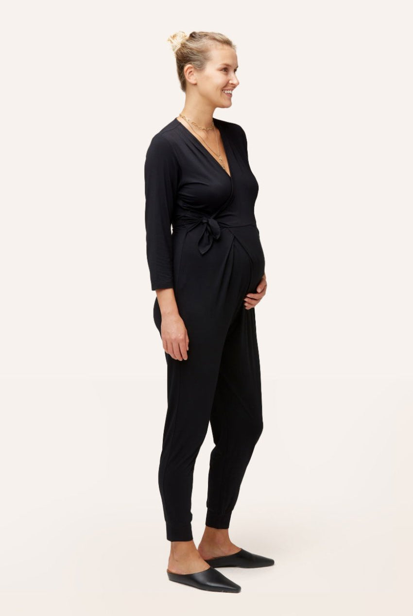 NOM Maternity Amabella Jumpsuit in Black, three-quarter view of wrap detail with bump