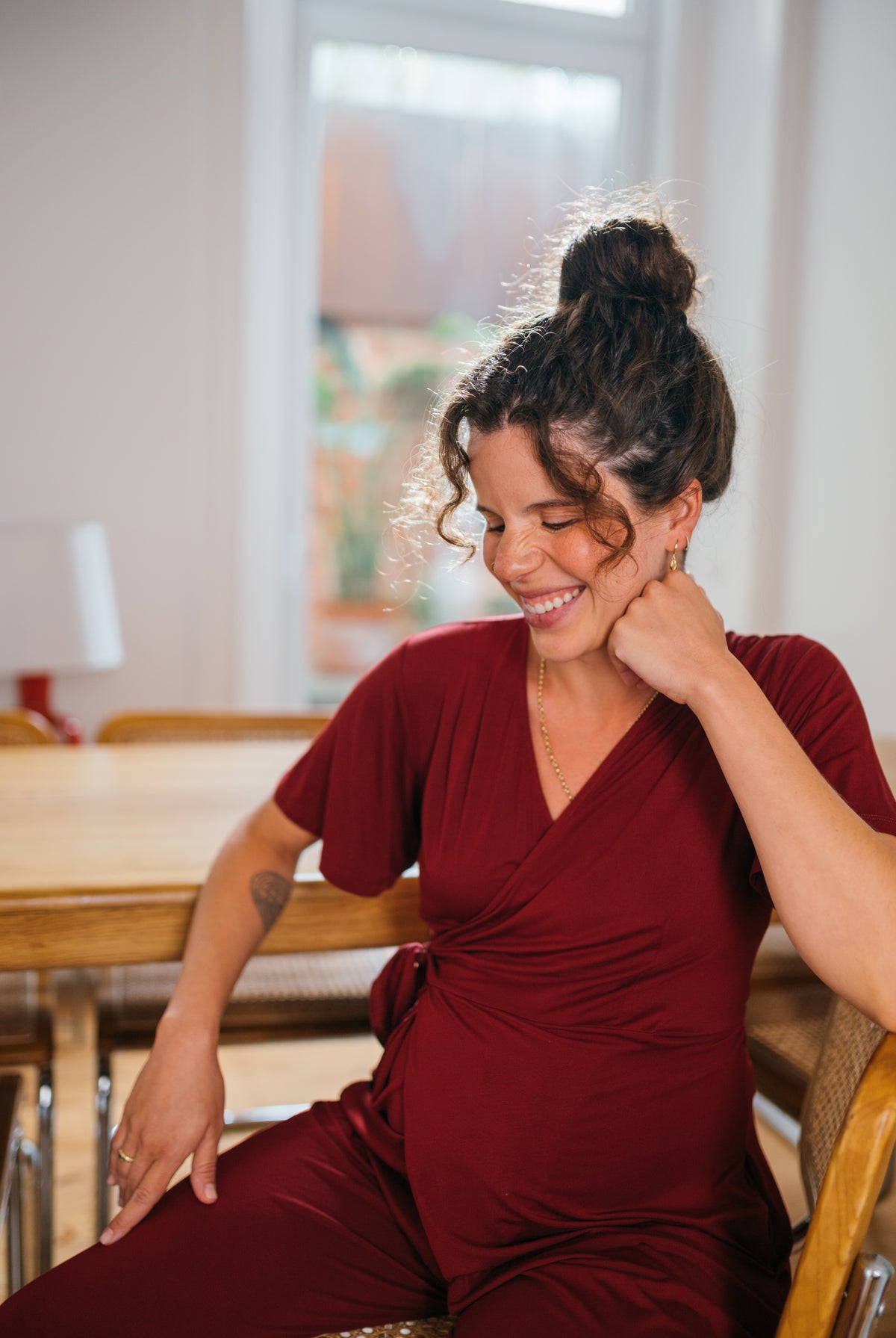 NOM Maternity Lucia Jumpsuit in Claret, lifestyle shot, showing front details, with bump