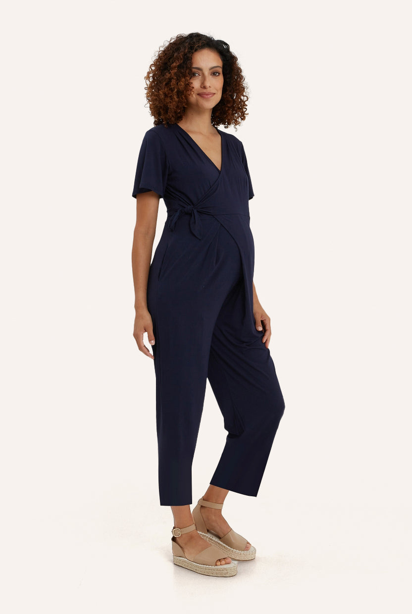 NOM Maternity Lucia Jumpsuit in Navy, three-quarter view showing wrap detail, with bump