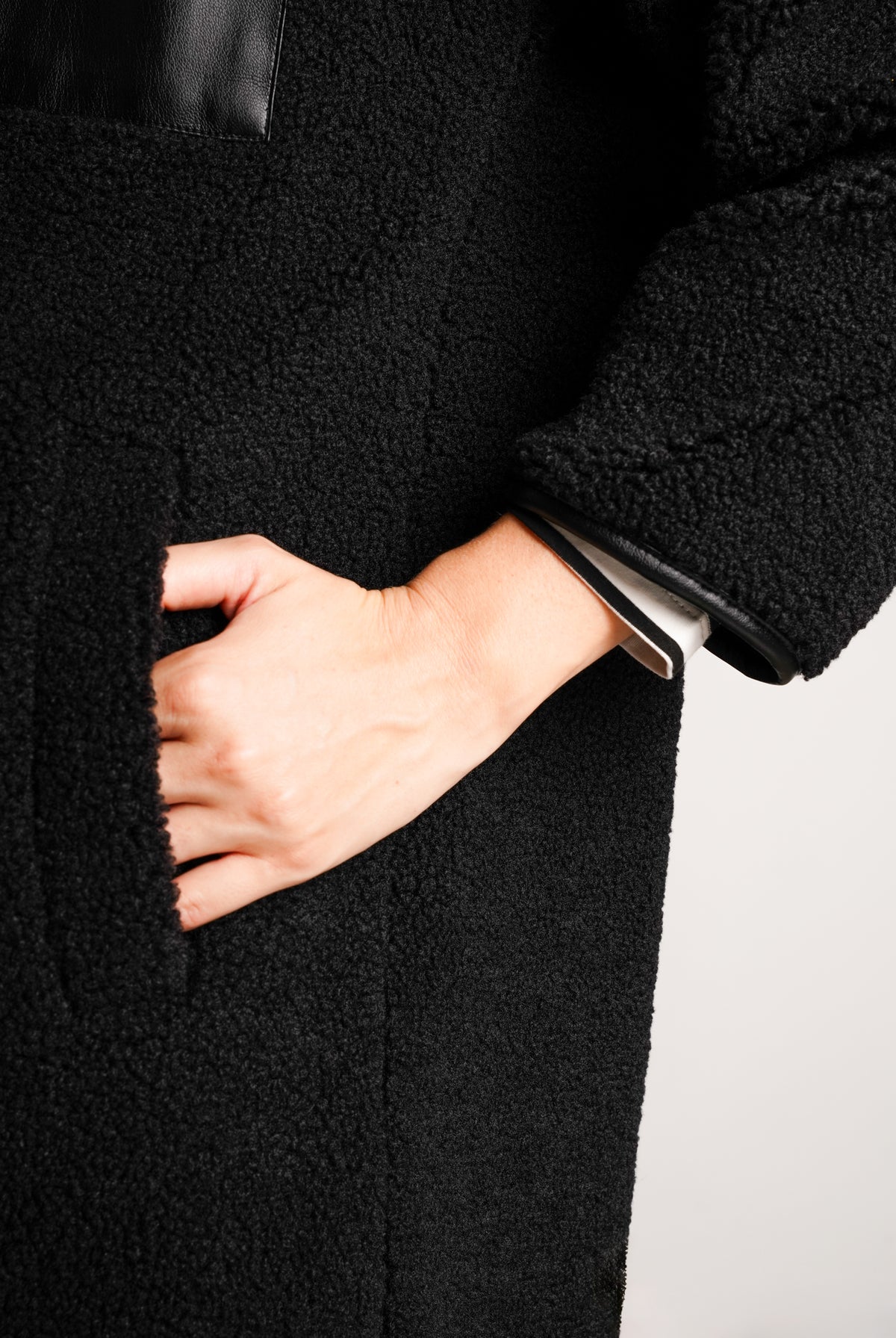NOM Maternity Teddi Coat in Black, close-up view showing pocket and sleeve cuff