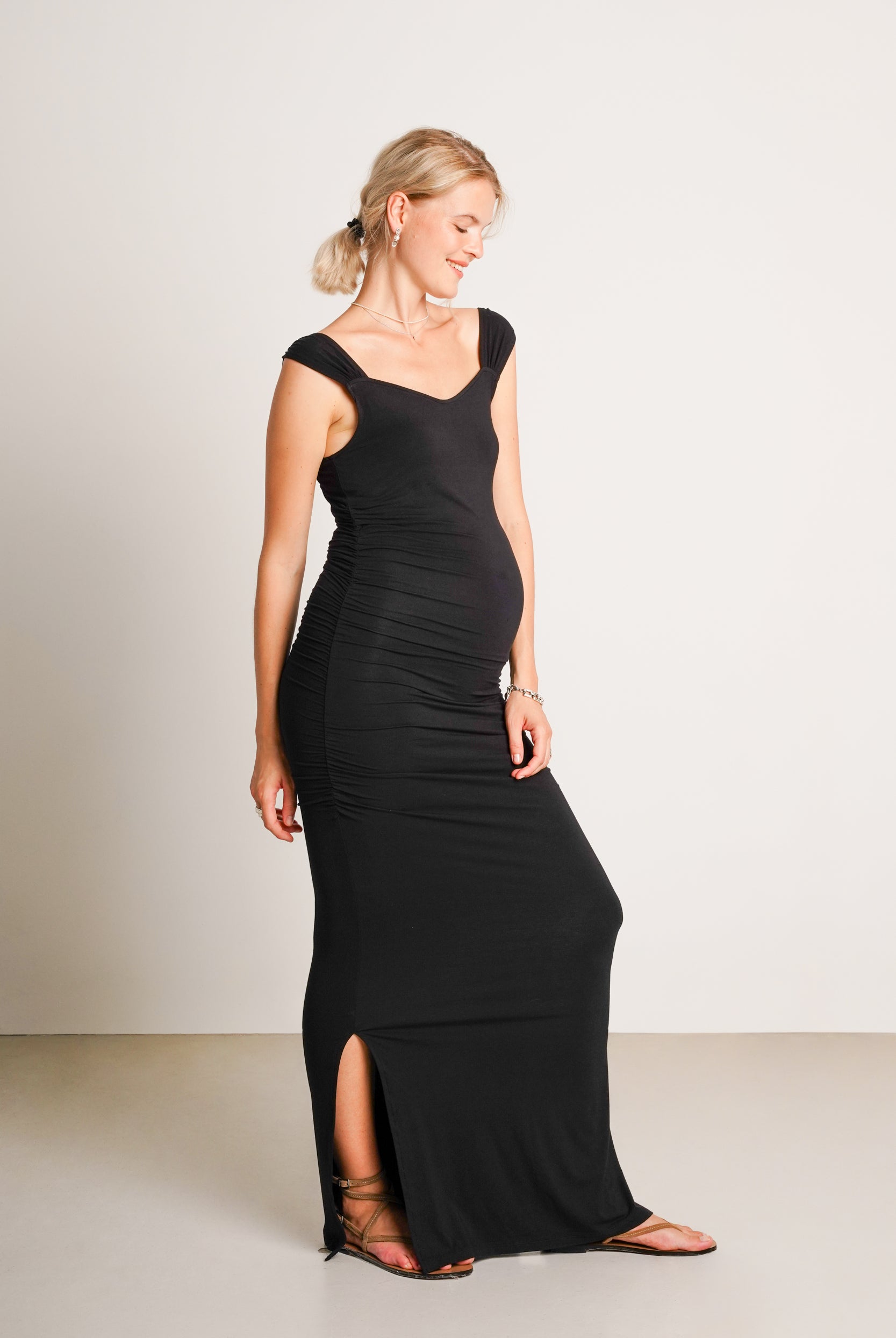 NOM Maternity Zoey Dress in Black, side view showing side slit and ruching with bump