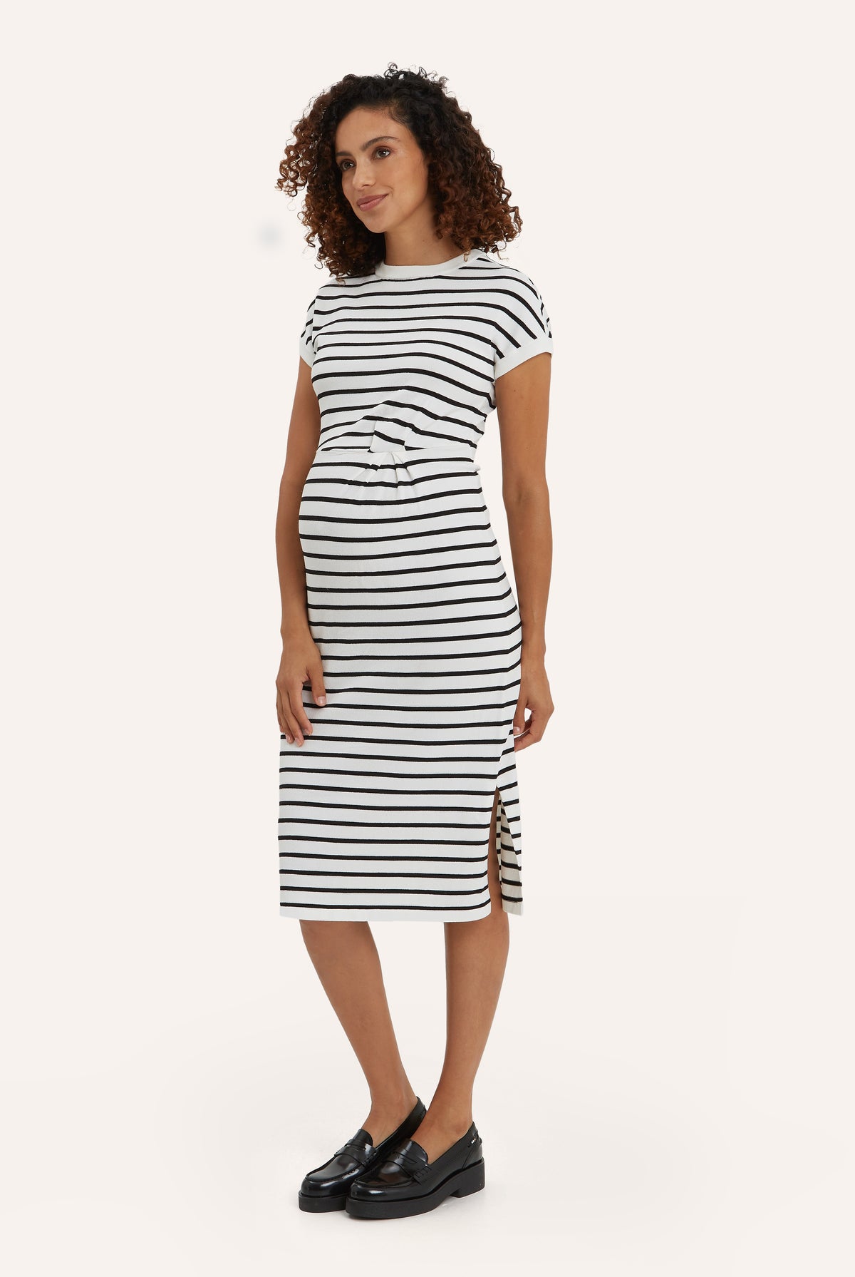 NOM Maternity Lydia Sweater Dress in Black & White Stripe, three-quarter view showing waist detail and side slit, with bump