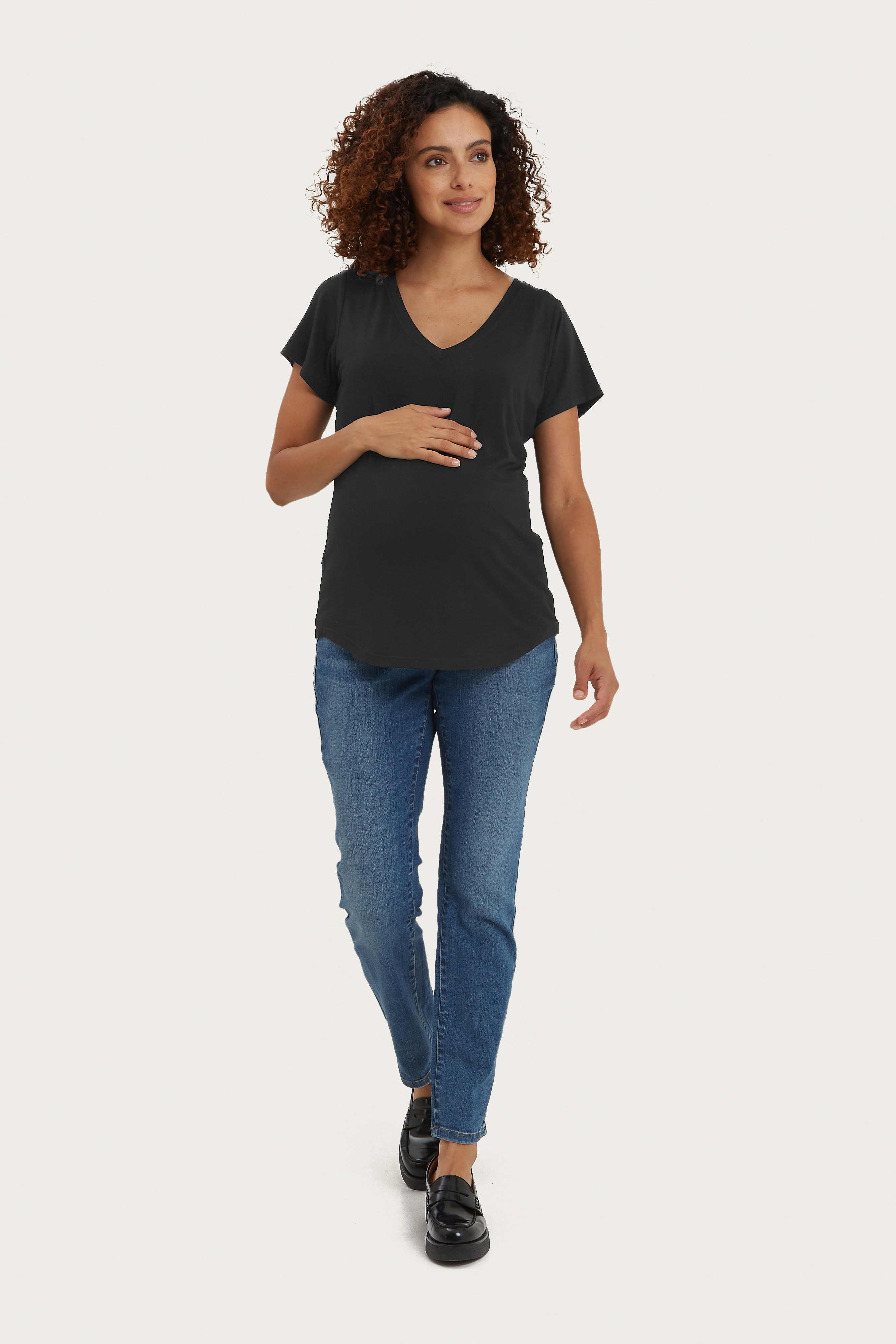Woman wearing a black V-neck t-shirt and blue jeans on a white background
